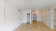 This single-floor, 2-bedroom, 2-bathroom residence offers a practical and well-organized layout designed for comfortable living. The entry opens into a bright foyer area with light tile flooring, a coat closet, and built-in shelving — ideal for storage and display. The living room is generously sized, featuring the same tile flooring, a ceiling fan with light fixture, and a sliding glass door that allows natural light to fill the space. A dedicated dining area adjoins the living space and includes a chandelier and additional built-in shelving. The galley-style kitchen is efficiently designed with white cabinetry, tile countertops, a double sink, electric range, and a full-size refrigerator, providing ample storage and prep space. Both bedrooms are carpeted and offer a comfortable, quiet retreat, each equipped with a closet featuring a full-length hanging rod. The bedrooms are served by two full bathrooms, each featuring a single-sink vanity with wood cabinetry, tile flooring, a large wall mirror, and a tub-shower combination with an arched surround. The overall design is clean and neutral, offering a versatile canvas throughout.