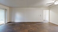 Located at 473 SE 169th Ave in Portland, Oregon, this single-floor, 2-bedroom, 2-bathroom home offers a practical and comfortable layout. The living room serves as the heart of the space, featuring rich dark hardwood-style flooring, a ceiling fan with light fixture, a textured ceiling, and a tiled fireplace that adds warmth and character. Sliding glass doors allow natural light to flow in and provide outdoor views. The kitchen is outfitted with white cabinetry, dark countertops, a full suite of white appliances including a refrigerator, dishwasher, and range, as well as a window overlooking the exterior. A dedicated in-unit laundry area with washer hookups and built-in shelving adds everyday convenience. Both bathrooms feature wood-style flooring, white vanities with dark countertops, and clean, neutral finishes; one includes a sliding glass shower enclosure. The two bedrooms are carpeted for comfort, each benefiting from natural light via windows with outdoor views. The primary bedroom includes a sliding double-door closet, and the home features a total of four closets throughout. A hallway connects the rooms, completing the efficient and well-organized floor plan.
