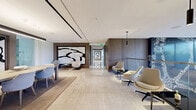 Located at 11750 Wilshire Blvd in Los Angeles, this refined amenity floor offers an expansive, single-level layout finished to the highest standards of contemporary design. The welcoming hallway serves as an elegant introduction, clad in large-format travertine-style stone flooring and adorned with striking large-scale abstract artworks framed in warm wood paneling. Pendant lighting and recessed fixtures create a polished, gallery-like atmosphere throughout.

The main lounge area features a warm wood-slat ceiling with integrated track lighting, built-in shelving, and a wall-mounted display panel, all centered around a relaxed seating arrangement ideal for gathering or unwinding. A private dining room is enclosed by floor-to-ceiling glass walls, flooding the space with natural light and offering direct access to the outdoor terrace. The sleek bar area presents a long white counter with wood barstool seating, backed by a dramatic marble wall display with integrated wine storage.

Additional seating alcoves provide flexible spaces for meetings or casual use, with glass-partitioned conference areas visible beyond. The expansive outdoor terrace completes the offering, featuring multiple dining and lounge seating arrangements, landscaped greenery, and open sky views across the surrounding Los Angeles streetscape — ideal for al fresco entertaining in the California sun.