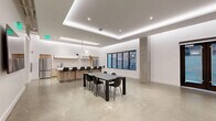 Located at 145 Leavenworth Street in San Francisco, this single-floor space offers a generously sized, open-plan layout designed with a clean, contemporary aesthetic. Polished concrete floors extend throughout, complementing the crisp white walls and lending an industrial-modern character to the interior.

The ceiling architecture is a defining feature, incorporating a recessed tray design with integrated LED cove lighting that casts a soft, ambient glow across the space. Recessed downlights provide additional illumination, ensuring the interior is well-lit throughout.

The kitchen is a central highlight, outfitted with light wood cabinetry, a marble-style backsplash, and sleek white upper cabinets. Stainless steel appliances, including two full-size refrigerators, a cooktop, and a sink with a matte black faucet, provide full functionality. A large island with a white countertop and black bar stools accommodates multiple guests, while a sculptural pendant light fixture adds an artistic touch overhead.

The open main area features a dining table with seating, a skylight for natural light, and dark-framed windows and French doors that face outward. A secondary zone includes a mounted display screen, seating, and interior access doors, making the space adaptable for various uses.