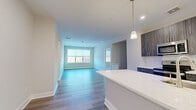 Located at 450 W Westfield Ave in Roselle Park, NJ, this well-appointed 2-bedroom, 2-bathroom residence offers a thoughtfully designed single-floor layout with modern finishes throughout. The open-concept living and kitchen area serves as the heart of the home, where wide-plank hardwood flooring flows seamlessly from the kitchen island to the spacious living room. Large windows invite an abundance of natural light, offering pleasant outdoor views. The kitchen is outfitted with sleek, dark wood cabinetry, white quartz countertops, stainless steel appliances including a range, microwave, and refrigerator, and a peninsula island with a built-in sink — all illuminated by stylish pendant lighting. The living area provides a bright, open atmosphere ideal for both relaxing and entertaining. Both bedrooms feature plush carpeting and generous windows with outdoor views. The primary bedroom includes access to a walk-in closet with wire shelving. The bathrooms are finished with large-format tile flooring, dark wood vanities topped with white counters, and contemporary lighting fixtures. Three additional closets and multiple hallways ensure practical storage throughout. The overall design is clean, modern, and move-in ready.