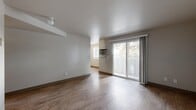 This 3-bedroom, 1-bathroom unit offers a practical and comfortable layout across a single floor. The living room is an open, airy space featuring wood-look laminate flooring, a textured ceiling, and a wall-mounted A/C unit. Sliding glass doors fill the room with natural light and provide direct access to a private balcony overlooking mature trees, bringing the outdoors in. The kitchen is well-equipped with dark espresso cabinetry, light granite-style countertops, and black appliances including a gas range and refrigerator, all complemented by matching wood-look flooring. Three bedrooms provide comfortable accommodations; the primary bedroom features plush carpeting and a sliding-door closet, while the additional bedrooms are finished with either carpet or wood-look flooring and include windows that frame pleasant outdoor views. The shared bathroom is clean and functional, featuring a soaking tub, grab bars, and consistent wood-look flooring. A connecting hallway ties the layout together efficiently. Neutral tones and consistent finishes throughout create a cohesive, move-in-ready aesthetic suited for everyday living.
