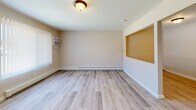 Located at 957 N Perry St in Pontiac, MI, this two-story home offers a practical and well-appointed layout spread across two floors. Light-toned wood-look flooring runs consistently throughout the space, creating a cohesive and clean aesthetic.

The main floor features a welcoming living room with a distinctive pass-through window opening to the kitchen, adding a sense of openness between the two areas. The kitchen is outfitted with white cabinetry, granite-look countertops, and includes a refrigerator — offering ample storage and prep space. A staircase with carpeted treads connects the main floor to the upper level.

Upstairs, two bedrooms provide comfortable accommodations. The primary bedroom includes a mirrored sliding closet door, a window unit for climate control, and baseboard heating. The second bedroom benefits from natural light through a window fitted with vertical blinds. Both rooms are served by a shared full bathroom, which features a granite-topped vanity with white cabinetry, a shower-tub combination, and wood-look flooring.

Throughout the home, neutral warm-beige walls, baseboard heating, and consistent flooring lend a clean, move-in-ready feel. The layout is efficient and functional, making thoughtful use of every area across both levels.