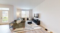 Located in Camby, Indiana, this 1-bedroom, 1-bathroom unit offers a thoughtfully designed single-floor layout with contemporary finishes and an efficient use of space. The open-concept kitchen and living area serves as the heart of the home, where light wood-tone flooring flows seamlessly throughout. The kitchen features sleek grey cabinetry, granite-look countertops, stainless steel appliances, and a generously sized center island with pendant lighting overhead — ideal for both meal preparation and casual dining. The adjacent living room is bright and welcoming, with large windows dressed in sheer curtains that invite natural light and offer outdoor views. The bedroom is comfortably sized, featuring soft carpeting, a ceiling fan, and windows that continue the theme of natural light. It connects directly to a dedicated walk-in closet equipped with wire shelving systems and light wood flooring, providing ample organized storage. The full bathroom is clean and modern, showcasing a granite-topped vanity with a framed mirror, warm wood-look flooring, and a well-lit, functional layout. The overall aesthetic is modern and neutral, with crisp white walls and consistent design choices that create a cohesive, move-in-ready living environment.
