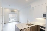 Located at 10015 113 St NW in Edmonton, Alberta, this thoughtfully designed one-bedroom, one-bathroom unit offers a clean, contemporary aesthetic throughout. Light-toned hardwood-style flooring and crisp white walls create a bright, cohesive atmosphere across the open-concept living space.

The kitchen is a standout feature, showcasing two-tone cabinetry — combining white upper cabinets with warm wood-grain lower cabinets and a matching island. Elegant marble-effect quartz countertops, a stainless steel sink with a pull-down faucet, and a full suite of stainless steel appliances including a refrigerator, range, microwave, and dishwasher complete the space. Recessed lighting provides ample illumination throughout.

The living area flows naturally from the kitchen and benefits from a sliding glass door that fills the room with natural light and offers outdoor views. A wall-mounted HVAC unit ensures year-round comfort.

The bedroom is a calm, sunlit retreat with a large window overlooking the surrounding neighbourhood and access to a well-organized walk-in closet. Two additional closets provide generous storage.

The bathroom is finished with marble-look tile, a sleek undermount sink set in quartz, warm wood-toned cabinetry, and a backlit LED mirror with polished chrome fixtures. In-unit laundry adds everyday convenience to this efficiently designed home.