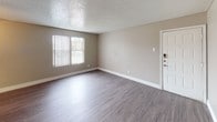 This single-story unit is designed with a consistent, neutral color palette of warm and cool grays throughout, creating a cohesive and modern aesthetic. Wood-look laminate flooring runs continuously across the living areas and bedrooms, adding warmth and visual continuity to the space.

The living area is open and well-proportioned, featuring a ceiling fan with integrated lighting, a textured popcorn ceiling, and a sliding vertical blind that leads to an exterior access point. Natural light enters through the windows, enhancing the brightness of the room. The layout connects directly to the kitchen, which is equipped with dark espresso cabinetry, granite-style countertops, a stainless steel single-basin sink, a dishwasher, and a white tile subway backsplash arranged in a grid pattern.

The unit includes multiple bedrooms, each featuring wood-look flooring, neutral gray walls, textured ceilings, and windows that bring in natural light. One bedroom includes an adjacent closet space. Both bathrooms follow a consistent design with dark vanity cabinetry, framed mirrors, subway tile backsplashes, white tub-shower combinations, and wood-look flooring, offering a polished and functional finish throughout.