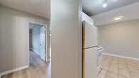 Located at 14921 104th Ave in Surrey, BC, this one-bedroom, one-bathroom unit offers a practical and comfortable layout across a single floor. The living room is the heart of the space, featuring light laminate hardwood flooring, neutral grey walls, and a large sliding glass door that opens to a private balcony with pleasant outdoor views of surrounding greenery — allowing natural light to fill the room. A baseboard heating system runs along the walls, ensuring year-round comfort. The kitchen is efficiently laid out with tile flooring, white appliances including a full-size refrigerator and stove, and is separated from the living area by a partial wall. The bedroom offers a comfortable footprint with the same light laminate flooring, neutral tones, and a set of sleek sliding-door closets providing ample built-in storage. A dedicated closet space adds further organizational convenience. The bathroom is finished with tile flooring, a tiled tub-shower surround in warm earth tones, a vanity with dark countertop, white cabinetry, and a large mirror. The textured ceilings and clean, simple design throughout give the unit a tidy, move-in-ready feel.