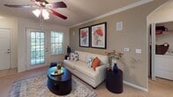 This single-floor residence showcases a well-organized layout with a warm, eclectic design aesthetic carried consistently throughout. The living room features crown molding, a ceiling fan, plush carpeting, and a wall-mounted TV, with natural light streaming in through a glass door that opens to the outdoors. Bold botanical artwork adds a lively focal point to the space.

The kitchen is a galley-style layout with light wood cabinetry, white appliances including a range, microwave, and refrigerator, and wood-look flooring that adds a clean, modern touch. Adjacent to the kitchen, the dining area features wainscoting, crown molding, and striking gold mandala-inspired artwork that creates an elegant, artistic atmosphere.

The primary bedroom is highlighted by a vibrant orange accent wall, plush carpeting, multiple windows with natural light, and a ceiling fan. A second bedroom offers a cozy, richly decorated space with a dark wood headboard accented by ornate orange-framed mirrors above.

Both bathrooms are well-appointed with single-sink vanities featuring wood cabinetry, large mirrors, tub-shower combinations with tiled surrounds, and wood-look flooring. The overall ambiance of the residence is warm and inviting, with a bold use of color, artistic wall décor, and cohesive design details throughout every room.