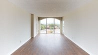 This 2-bedroom, 2-bathroom unit is designed with a practical, single-story layout that makes efficient use of its space. The living area serves as the centerpiece of the unit, featuring rich wood-style flooring and a striking floor-to-ceiling arched sliding glass door that opens to a balcony with expansive city skyline views, flooding the room with natural light.

The galley-style kitchen is positioned adjacent to the living area and features wood-toned cabinetry extending to the ceiling, a double stainless steel sink, a coil-burner range, a refrigerator, and a dishwasher. Overhead lighting and ample counter space make the kitchen both functional and practical.

Both bedrooms are carpeted and well-proportioned, each offering large sliding-door closets that provide generous storage capacity. One bedroom also features access to an additional closet, further enhancing storage options. Large sliding glass doors in the bedrooms bring in natural light and offer elevated outdoor views.

The two bathrooms differ in configuration. The primary bathroom includes a full-width vanity mirror with globe lighting, a single sink, a tiled shower-tub combination, and wood-style flooring. The second bathroom features a narrower layout with a countertop vanity, toilet, and tub, also finished with wood-style flooring. Both bathrooms maintain a clean, neutral aesthetic consistent with the rest of the unit.