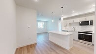 Located at 1151 Encanto Loop in Chula Vista, California, this modern 2-bedroom, 2-bathroom residence offers a thoughtfully designed open-concept layout with clean, contemporary finishes throughout. Light wood-style flooring flows seamlessly across the living spaces, complementing the bright white walls and creating a fresh, airy ambiance.

The kitchen is a standout feature, showcasing white shaker cabinetry with matte black hardware, a white subway tile backsplash, quartz countertops, and a large center island with pendant lighting overhead. Stainless steel appliances — including a refrigerator with ice maker, dishwasher, and range — complete the well-appointed space, which opens directly into the living area.

The generously sized primary bedroom includes access to a walk-in closet with wire shelving, offering ample storage. The second bedroom is bright and well-proportioned, with windows framing neighborhood views. Both bathrooms feature white tiled tub-shower combos with chrome fixtures and wood-style flooring, maintaining the home's clean aesthetic. One bathroom includes additional built-in cabinetry for extra storage.

Two closets across the unit provide practical organization options. Natural light fills each room through multiple windows, enhancing the home's open, welcoming feel throughout.