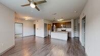Located at 2509 Cattlemen Rd in Sarasota, FL, this well-appointed single-story residence offers two bedrooms and two bathrooms within a thoughtfully designed floor plan. The open-concept living, dining, and kitchen area forms the heart of the home, anchored by a central island with granite countertops, pendant lighting, and a stainless steel sink. The kitchen is outfitted with rich dark wood cabinetry, stainless steel appliances including a refrigerator, range, and microwave, complemented by a tile backsplash and a pantry for additional storage. Wood-style flooring runs throughout the main living areas, while ceiling fans provide comfort in both the living room and bedrooms. The bedrooms are carpeted and bright, each featuring a ceiling fan and generous closet space — including a walk-in closet with wire shelving in the primary bedroom. The bathrooms mirror the kitchen's finishes, with granite-topped dark wood vanities and tiled tub-shower combinations. A dedicated in-unit laundry room adds everyday convenience, and a private patio extends the living space outdoors. Natural light filters through blinds-fitted windows throughout, creating a clean, contemporary ambiance.