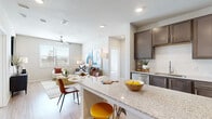 This single-floor residence offers a thoughtfully designed open-concept layout that seamlessly connects the kitchen, dining, and living areas. The kitchen is a standout feature, showcasing rich dark-brown cabinetry, a full suite of stainless steel appliances including a French door refrigerator, electric range, built-in microwave, and dishwasher, all complemented by granite countertops and a classic subway tile backsplash. A central island with bar seating provides additional workspace and casual dining options. Light wood-style flooring flows throughout the space, enhancing the bright, airy atmosphere created by recessed lighting and natural light streaming through large windows fitted with horizontal blinds. The living area is generously sized, complete with a ceiling fan and views to the outdoors. The bedrooms are well-proportioned, sun-filled spaces with the same wood-style flooring and ample natural light. The bathrooms mirror the kitchen's elevated finishes, featuring granite-topped dark vanities, soaking tubs with subway tile surrounds, and direct access to spacious walk-in closets with built-in shelving. The overall aesthetic is clean, contemporary, and cohesive, making this a comfortable and well-equipped living space.