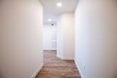 This single-story space offers a clean, contemporary design characterized by crisp white walls, light wood-look flooring in the main living areas, and plush carpet in the bedrooms. The layout, as revealed by the floor plan, includes a well-proportioned living area bathed in natural light from multiple windows fitted with white blinds, connecting seamlessly to the rest of the unit via a neat hallway with recessed lighting.

The kitchen is a functional highlight, equipped with rich dark-stained cabinetry, light-toned countertops, a double-basin stainless steel sink, and a full suite of stainless steel appliances including a refrigerator, range, microwave, and dishwasher. A window above the sink provides natural light to the workspace.

The bedrooms are comfortably sized, each featuring plush neutral carpet, ceiling fans with light fixtures, and windows that allow natural light to filter in. The two bathrooms follow a consistent design language, each offering a tub-shower combination with built-in shelving, a dark wood vanity with a single sink, light countertops, a large mirror, and wood-look flooring, providing a cohesive and practical aesthetic throughout the space.