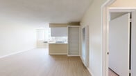 Located at 456 South Harvard Boulevard in the heart of Los Angeles, Unit 205 is a well-appointed one-bedroom, two-bathroom residence offering a thoughtfully designed single-level layout. Light wood-tone flooring runs throughout, complementing the warm neutral tones of the walls and creating a bright, cohesive atmosphere across all rooms.

The open living area is generously proportioned, with a textured ceiling and clean white baseboards framing the space. It flows naturally toward the kitchen, which features a peninsula with a gas cooktop, white cabinetry, ample counter space, and a full suite of white appliances including a gas range and refrigerator. Natural light enters through a window above the sink, brightening the galley-style workspace.

The primary bedroom offers a comfortable footprint with a window that frames views of the surrounding Los Angeles streetscape, including palm trees and neighboring architecture, adding an unmistakable urban character to the room.

The bathrooms are a notable highlight — one features a beautifully finished walk-in shower with floor-to-ceiling marble-style tile, a frameless glass sliding door, and hexagonal mosaic floor tiles, lending a refined, spa-like quality. White cabinetry and clean finishes complete both bathrooms. The unit's overall design is clean, functional, and well-suited for comfortable city living.
