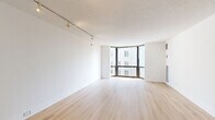 Located in Chicago's prestigious Gold Coast neighborhood, this one-bedroom, one-bathroom residence at 1111 North Dearborn Street offers a well-designed layout across a single floor. The living room is the centerpiece of the space, featuring light-toned hardwood flooring, crisp white walls, and a textured ceiling with track lighting. A dramatic curved floor-to-ceiling window wall floods the room with natural light and frames views of the surrounding Chicago cityscape, creating an open and airy atmosphere.

The kitchen is efficiently appointed with rich dark-wood cabinetry, light countertops, a classic white subway tile backsplash, a stainless steel sink, and black appliances including a full-size refrigerator. The generously sized primary bedroom also benefits from the building's expansive window system, allowing natural light to pour in. A dedicated closet area provides ample storage with full-length hanging rods and upper cabinet shelving.

The bathroom features a classic black-and-white mosaic tile floor, a single vanity with a white basin, and a tub-shower combination. The dedicated entrance and thoughtful layout contribute to a functional flow throughout the residence. Light hardwood flooring runs consistently through the main living areas, tying the space together with warmth and cohesion.