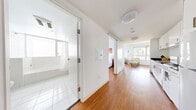 Located at 1188 Mission Street in the heart of San Francisco, this well-appointed single-floor residence offers a clean, modern aesthetic throughout. Warm hardwood flooring runs continuously across the main living areas, complementing the crisp white walls and creating a bright, cohesive atmosphere.

The living room is a standout space, anchored by expansive floor-to-ceiling windows on two sides that flood the room with natural light and frame sweeping panoramic views of the San Francisco skyline. The open layout comfortably accommodates a seating area and a separate dining space.

The kitchen is efficiently designed with white cabinetry, a full-size refrigerator, a gas range, and ample counter space — ideal for everyday cooking. A dedicated workspace area with a window provides natural light and city views, making it well-suited for remote work or study.

The bedroom is calm and restful, featuring large windows with city views, warm hardwood floors, and accents of curated artwork. A full bathroom offers white tile flooring, a soaking tub with shower, built-in shelving, and a large vanity mirror, maintaining the home's clean and minimal design language.

A hallway with a sliding barn door connects the main areas smoothly, reinforcing the unit's thoughtful, contemporary layout.