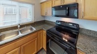 Located at 1501 S Highland Ave in Fullerton, California, this single-floor unit offers a thoughtfully designed layout with a comfortable, functional living environment. Throughout the space, wood-look flooring provides a cohesive and modern aesthetic, while neutral-toned walls create a clean, versatile backdrop.

The living area is generously proportioned, featuring a ceiling fan with light fixture, crown molding accents, and a sliding glass door that opens to a private balcony overlooking lush greenery — allowing natural light to pour into the space. A wall-mounted air conditioning unit ensures year-round comfort.

The kitchen is well-appointed with warm maple cabinetry, dark granite countertops, a stainless steel sink, and black appliances including an electric range and over-the-range microwave. A window above the sink brings in natural light, making the space bright and practical.

The bedrooms are comfortably sized, each featuring ceiling fans with light kits and windows fitted with blinds that offer both privacy and natural light. The rooms are finished with the same wood-look flooring found throughout the unit.

The bathrooms provide distinct options: one features a pedestal sink, a combination tub and shower with a sliding glass enclosure, and wood-look flooring; while the other offers an expansive vanity with granite countertops, ample cabinetry, and a large mirror with overhead lighting.