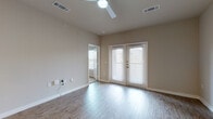 This single-floor unit offers a clean, modern design throughout its well-organized layout. The open-concept living area is finished with light wood-look hard flooring and neutral beige walls, creating a bright and airy atmosphere. A ceiling fan with an integrated light fixture provides both comfort and illumination, while a set of French doors fitted with white blinds allows natural light to filter in and provides access to the outdoors.

The kitchen is a functional highlight of the space, featuring white shaker-style cabinetry extending to the ceiling for ample storage, quartz-style countertops, a double-basin stainless steel sink, and a full suite of stainless steel appliances including a refrigerator, electric range, over-the-range microwave, and dishwasher. Light wood flooring and pendant lighting complete the kitchen's contemporary look. A breakfast bar countertop separates the kitchen from the living area, enhancing the open feel.

The bedroom is finished with soft wall-to-wall carpeting and continues the neutral color palette, offering a comfortable and quiet retreat with a ceiling fan overhead.

The bathroom is efficiently designed, featuring a full soaking tub with an overhead shower, white subway tile surround, chrome fixtures, and wood-look flooring, all maintained in a clean, minimalist style.