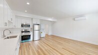 This one-bedroom, one-bathroom unit at 3630 Midvale Avenue in Los Angeles offers a clean, modern aesthetic throughout its efficiently designed single-floor layout. Light-toned hardwood flooring runs continuously across every room, creating a cohesive and airy feel that amplifies the natural light admitted through horizontal slatted windows in both the bedroom and living areas.

The open kitchen and living room share a generous combined footprint, forming the heart of the unit. The kitchen features floor-to-ceiling white shaker cabinetry, white subway tile backsplash, light quartz countertops, and a full suite of stainless steel appliances including a gas range, dishwasher, microwave, and refrigerator. A stacked washer and dryer unit is conveniently integrated into the kitchen area.

The living room is bright and open, with a wall-mounted mini-split system providing individual climate control. The bedroom offers a comfortable, well-proportioned space with its own mini-split unit, a wide window for natural light, and a sliding-door closet.

The bathroom is finished with marble-style tile surrounding a full soaking tub and shower combination, complemented by brushed gold fixtures, a white vanity, and a privacy window. Clean white walls and crisp trim throughout give the entire unit a fresh, move-in-ready appearance.