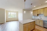 Located at 7592–7594 Buckley Rd in Syracuse, NY, this single-floor, 2-bedroom, 2-bathroom home offers a thoughtfully designed layout with modern finishes throughout. The open-concept kitchen is a standout feature, showcasing warm maple cabinetry, granite countertops, a subway tile backsplash, and stainless steel appliances including a range, microwave, and refrigerator. A central kitchen island with pendant lighting adds both function and style, flowing seamlessly into the adjacent dining area, which is brightened by a multi-pane window and elegant chandelier. Light hardwood flooring runs throughout the main living areas, lending a clean and cohesive aesthetic. The spacious primary bedroom offers generous proportions and includes a walk-in closet fitted with wire shelving for ample storage. The bathrooms feature large-format tile flooring, warm wood vanities with white countertops, and well-lit mirrors. A dedicated laundry room houses a full-size washer and dryer alongside the water heater and electrical panel, adding practical convenience. Neutral wall tones and textured ceilings complete the interior, creating a bright, move-in-ready home suitable for a variety of lifestyles.