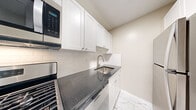 Located at 8200 Wisconsin Avenue in the heart of Bethesda, MD, this one-bedroom, one-bathroom residence offers a well-organized layout with a cohesive, updated aesthetic throughout. Polished parquet wood flooring flows continuously through the living room and bedroom, lending warmth and character to the space.

The living room is bright and open, anchored by floor-to-ceiling sliding glass doors that lead to a balcony and frame sweeping panoramic views of the surrounding Bethesda skyline and beyond. A ceiling fan adds comfort, and the textured ceiling complements the room's clean, neutral palette.

The kitchen has been thoughtfully renovated, featuring white shaker cabinetry, dark granite countertops, a classic white subway tile backsplash, and marble-look porcelain tile flooring. Stainless steel appliances — including a refrigerator, built-in microwave, and dishwasher — complete the functional and stylish space.

The bedroom is a comfortable, well-lit retreat with its own window offering elevated outdoor views and the same warm parquet flooring. Two closets provide generous storage throughout the unit.

The bathroom is finished with granite counters, a brushed nickel faucet, and neutral tile surrounding the shower, creating a clean and refined look. The overall design is understated and move-in ready.
