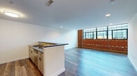 This two-floor residence masterfully combines industrial character with contemporary design. The main level centers on an open-concept living and kitchen area distinguished by a striking exposed brick accent wall and large steel-framed windows that flood the space with natural light and offer outward views. Wood-style flooring runs throughout, complementing the clean white walls and recessed lighting overhead. The kitchen is well-appointed with light wood cabinetry, dark granite countertops, stainless steel appliances including an electric range and built-in microwave, and a subway tile backsplash. A peninsula with a sink adds functional workspace and a natural division between the kitchen and living area. A powder room on the main level features a wood vanity with a dark granite top and an undermount sink. The upper floor offers carpeted rooms bathed in natural light from skylights, lending a quieter, more intimate atmosphere. In-unit laundry with a full-size washer and dryer is conveniently tucked into a dedicated closet on this level. Bathrooms include a full bath with large-format stone-look tile surrounding a soaking tub, and an additional bath finished with matching tile flooring and a wood vanity with a white countertop.