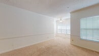 This single-floor 1-bedroom, 1-bathroom residence offers a thoughtfully designed layout that balances comfort and functionality. The spacious living area is finished with neutral-toned carpeting and crisp white walls accented by a chair rail, creating a clean and welcoming atmosphere. A ceiling fan with a light fixture provides both airflow and ambient lighting, while a large window invites natural light into the space.

The living area flows seamlessly into a dining area, illuminated by an elegant chandelier, and connects to the kitchen through a convenient pass-through counter. The kitchen is well-equipped with rich dark-wood cabinetry, ample counter space with light-toned surfaces, a stainless steel range, and tile flooring, providing both style and practicality for everyday cooking.

The bedroom is generously sized, featuring the same warm carpeting found throughout the living areas, a ceiling fan, and a set of French doors that open to the outdoors, offering natural light and private exterior access.

The bathroom is finished with tile flooring and features a dark-wood vanity with a single sink, a well-lit mirror, and a combined tub and shower, providing a clean and functional space. Overall, this residence presents a cohesive, neutral palette with practical finishes throughout.