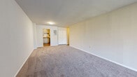 Located at 5 Stonewain Ct in Towson, Maryland, this well-appointed one-bedroom, one-bathroom residence offers a thoughtfully designed single-level layout. The expansive living room is a standout feature, with plush wall-to-wall carpeting and a large sliding glass door that floods the space with natural light and opens to an outdoor view. A closet with sliding doors is conveniently positioned off the living area. The kitchen is efficiently designed with crisp white shaker-style cabinetry, granite countertops, a stainless steel sink, and black appliances including a gas range, microwave, and dishwasher, all set on wood-look plank flooring. A hallway connects the main living area to the generously sized bedroom, which features carpeted floors, a natural light window, and access to multiple closets providing ample storage. The bathroom is neatly finished with wood-tone vanity cabinetry, a white countertop, a large mirror, a tub-shower combination, and wood-style tile flooring. Neutral tones throughout create a clean, move-in ready ambiance. With three total closets, this residence offers exceptional storage for its size.