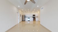 This single-floor unit offers a clean, modern design centered around an open-concept living and kitchen area. Highly polished large-format tile flooring runs throughout the entire space, reflecting natural and recessed lighting to create a bright, airy ambiance. Tray ceilings with recessed lighting add architectural interest to the main living area, which is further complemented by a ceiling fan and generous wall space for flexible furniture arrangements. Large windows fitted with horizontal blinds allow natural light to fill the bedrooms, each of which features its own ceiling fan and a well-proportioned closet with bifold doors and built-in hanging rods. The kitchen is designed with functionality in mind, showcasing high-gloss white cabinetry extending to the ceiling, light-toned countertops, and a full suite of stainless steel appliances including a refrigerator, range, microwave, and dishwasher. Two full bathrooms serve the unit — one featuring a tub-shower combo alongside a washer/dryer unit, offering convenient in-unit laundry, and the other a walk-in shower with white tile surround. Both bathrooms maintain the unit's crisp, all-white aesthetic with modern fixtures and vanities. An electrical panel is accessible from the main living area, adding practical utility to this well-appointed space.