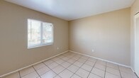Located at 8372 Beacon Blvd in Fort Myers, FL, this one-bedroom, one-bathroom unit offers a functional and efficient single-floor layout. The combined living and dining area serves as the heart of the unit, featuring light beige walls, neutral-toned tile flooring, and a textured ceiling throughout. A centered window brings in natural light, creating a bright and open atmosphere. A freestanding kitchen island with warm wood cabinetry and a granite-style countertop bridges the living space and kitchen, offering additional prep and storage space. The kitchen itself is efficiently designed with matching wood cabinetry, granite-style countertops, and black appliances including a range and a full-size refrigerator. The bedroom is a comfortable, well-proportioned space with the same tile flooring, neutral walls, and a window that allows natural light to filter in. Two closets provide ample storage throughout the unit. The hallway connects the main living areas to the bedroom and bathroom, which features a wood-cabinet vanity, a white countertop with an integrated sink, and a medicine cabinet mirror. The overall layout is practical and cohesive, well-suited for everyday living in a warm Florida setting.