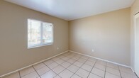 Located at 8372 Beacon Blvd in Fort Myers, FL, this one-bedroom, one-bathroom unit offers a functional and efficient single-floor layout. The combined living and dining area serves as the heart of the unit, featuring light beige walls, neutral-toned tile flooring, and a textured ceiling throughout. A centered window brings in natural light, creating a bright and open atmosphere. A freestanding kitchen island with warm wood cabinetry and a granite-style countertop bridges the living space and kitchen, offering additional prep and storage space. The kitchen itself is efficiently designed with matching wood cabinetry, granite-style countertops, and black appliances including a range and a full-size refrigerator. The bedroom is a comfortable, well-proportioned space with the same tile flooring, neutral walls, and a window that allows natural light to filter in. Two closets provide ample storage throughout the unit. The hallway connects the main living areas to the bedroom and bathroom, which features a wood-cabinet vanity, a white countertop with an integrated sink, and a medicine cabinet mirror. The overall layout is practical and cohesive, well-suited for everyday living in a warm Florida setting.