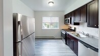 Located at 350 Parsippany Rd in Parsippany, NJ, this single-floor, one-bedroom, one-bathroom residence offers a well-organized and functional layout. The living area is a standout feature, showcasing warm-toned hardwood flooring that runs throughout most of the unit, neutral white walls, and a large window that allows generous natural light to fill the space. A wall-unit air conditioner and baseboard heating provide year-round climate control. The kitchen is thoughtfully appointed with rich dark cabinetry, a gas range, stainless steel microwave, and a full-size refrigerator, complemented by a window overlooking greenery outside. Light-toned luxury vinyl flooring in the kitchen adds a clean contrast to the rest of the home. The bedroom continues the hardwood flooring theme and includes a double-door closet and a wide window that brings in additional natural light. The bathroom features classic white subway tile surrounding a full bathtub and shower combination, with a window providing ventilation and soft light. Throughout the unit, clean lines, neutral tones, and practical finishes create a cohesive and move-in-ready living environment suited for comfortable everyday living.