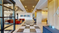 Located at 2226 North Davidson Street in Charlotte's NoDa neighborhood, this single-floor amenity space offers a thoughtfully designed environment spanning a generous footprint. The main lobby welcomes visitors with a striking checkered marble tile floor, warm wood-slat ceiling accents, and recessed lighting that creates an inviting, upscale atmosphere. A welcoming wall feature reads "It's so good to be home," setting a warm tone from the moment of entry.

The central lounge area is anchored by plush rust-orange velvet seating arrangements, complemented by curated artwork along the crisp white walls and layered area rugs that define each zone. Tiered ceiling details with decorative pendant and track lighting add depth and visual interest throughout.

A separate lounge zone features warm gold-toned wall paneling, a wall-mounted flat-screen television, and an eclectic mix of neutral furnishings arranged around a bold, colorful area rug. Floor-to-ceiling glass doors and large windows flood the space with natural light and provide views of the surrounding streetscape.

The dining and co-working area offers multiple seating configurations, glass-partitioned office rooms, light wood flooring, and statement pendant lighting. Two dedicated office spaces provide functional workspaces. The overall design balances contemporary sophistication with comfort, making it an ideal communal hub.