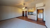 Located in Pulaski, Wisconsin, this single-floor unit offers a well-designed, functional layout with a comfortable mix of carpeted and hardwood-style flooring throughout. The open-concept living and kitchen area serves as the heart of the space, where a ceiling fan with light fixture anchors the vaulted ceiling above the carpeted living area. Sliding glass doors lead to a private balcony, filling the room with natural light and providing outdoor access. The kitchen is efficiently equipped with stainless steel appliances — including a refrigerator, electric range, and over-the-range microwave — complemented by warm-toned wood cabinetry, granite-style countertops, and a peninsula that adds extra prep and seating space. Track lighting overhead ensures the kitchen is well-lit. Two generously sized bedrooms each feature plush carpeting, large windows that bring in ample natural light, and baseboard heating. The unit includes two bathrooms: one with a walk-in shower and wood-tone cabinetry, and another full bathroom featuring a soaking tub, a wide vanity with granite-style countertops, and hardwood-style flooring. This unit offers a practical and comfortable living environment in a quiet Pulaski community setting.