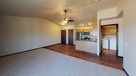 Located in Pulaski, Wisconsin, this single-floor unit offers a well-designed, functional layout with a comfortable mix of carpeted and hardwood-style flooring throughout. The open-concept living and kitchen area serves as the heart of the space, where a ceiling fan with light fixture anchors the vaulted ceiling above the carpeted living area. Sliding glass doors lead to a private balcony, filling the room with natural light and providing outdoor access. The kitchen is efficiently equipped with stainless steel appliances — including a refrigerator, electric range, and over-the-range microwave — complemented by warm-toned wood cabinetry, granite-style countertops, and a peninsula that adds extra prep and seating space. Track lighting overhead ensures the kitchen is well-lit. Two generously sized bedrooms each feature plush carpeting, large windows that bring in ample natural light, and baseboard heating. The unit includes two bathrooms: one with a walk-in shower and wood-tone cabinetry, and another full bathroom featuring a soaking tub, a wide vanity with granite-style countertops, and hardwood-style flooring. This unit offers a practical and comfortable living environment in a quiet Pulaski community setting.