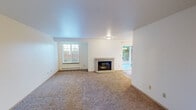 This single-floor unit at 2788 Danbury Ln SW in Tumwater, Washington offers a thoughtfully laid-out interior with a blend of practical and comfortable features throughout. The living room serves as the central gathering space, anchored by a brick-surround fireplace with glass doors, plush carpeting underfoot, and a sliding glass door that opens to an outdoor patio, allowing natural light and views of the surrounding greenery to flow inward. A dedicated window alcove provides additional natural light and frames outdoor foliage.

The dining area transitions seamlessly from the living space, featuring light wood-look flooring and an elegant chandelier, with its own sliding glass door reinforcing the connection to the outdoors. The kitchen is equipped with white cabinetry, granite-style countertops, white appliances, and a convenient walk-in pantry with built-in shelving. A peninsula counter provides additional workspace.

The bedrooms are carpeted and well-proportioned, each with windows fitted with blinds and baseboard heating. At least one bedroom includes a walk-in closet with a rod and shelving. The bathroom features a white vanity with a granite-style countertop, a large mirror, a tub-shower combination, and wood-look flooring, completing this clean and functional space.