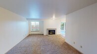 This single-floor unit at 2788 Danbury Ln SW in Tumwater, Washington offers a thoughtfully laid-out interior with a blend of practical and comfortable features throughout. The living room serves as the central gathering space, anchored by a brick-surround fireplace with glass doors, plush carpeting underfoot, and a sliding glass door that opens to an outdoor patio, allowing natural light and views of the surrounding greenery to flow inward. A dedicated window alcove provides additional natural light and frames outdoor foliage.

The dining area transitions seamlessly from the living space, featuring light wood-look flooring and an elegant chandelier, with its own sliding glass door reinforcing the connection to the outdoors. The kitchen is equipped with white cabinetry, granite-style countertops, white appliances, and a convenient walk-in pantry with built-in shelving. A peninsula counter provides additional workspace.

The bedrooms are carpeted and well-proportioned, each with windows fitted with blinds and baseboard heating. At least one bedroom includes a walk-in closet with a rod and shelving. The bathroom features a white vanity with a granite-style countertop, a large mirror, a tub-shower combination, and wood-look flooring, completing this clean and functional space.