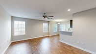 This single-story, 1-bedroom, 1-bathroom residence offers a thoughtfully designed layout that maximizes functionality and comfort. The open-concept living room serves as the heart of the home, featuring rich hardwood flooring, a textured ceiling, recessed lighting, and a ceiling fan. Multiple windows dressed with white blinds fill the space with natural light, while a kitchen pass-through with a built-in sink connects seamlessly to the living area. The kitchen is well-equipped with dark wood cabinetry, white quartz countertops, a tile backsplash, and stainless steel appliances, including a range, microwave, refrigerator, and double-basin sink. The spacious bedroom is finished with plush carpeting and a ceiling fan, and it connects to a generous walk-in closet outfitted with dual wire shelving systems. The bathroom features hardwood-style flooring, a tub/shower combination, and a dark wood vanity consistent with the kitchen's design aesthetic. The dedicated laundry area includes an in-unit washer and wire shelving for additional storage. Neutral gray tones throughout the home create a clean, cohesive aesthetic well-suited for a variety of living styles.