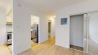 Located at 855 Jervis Street in Vancouver's West End, this efficiently designed studio offers a thoughtfully laid-out single-floor plan comprising a combined kitchen and living area, a closet, and a full bathroom. Light wood laminate flooring runs throughout the living spaces, creating a bright and cohesive aesthetic.

The kitchen is well-appointed with white shaker-style cabinetry, light stone countertops, a grey subway tile backsplash, and a full suite of stainless steel appliances including a refrigerator, electric range, and dishwasher. A peninsula counter provides additional workspace and a natural division between the kitchen and living area.

The open living room is bathed in natural light from a large window fitted with vertical blinds, offering views of the surrounding neighbourhood. A wall-mounted radiator provides in-suite heating. The space is finished with clean white walls that enhance the sense of openness.

The closet features mirrored sliding doors and built-in hanging storage, maximizing functionality in a compact footprint. The bathroom is finished with grey tile surrounds on the tub-shower combo, a white vanity with under-sink storage, a medicine cabinet mirror, and tile flooring, delivering a clean and modern feel throughout.