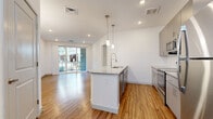 Located in Phoenix, AZ, this well-appointed 1-bedroom, 1-bathroom unit offers a thoughtfully designed open-concept layout that maximizes every square foot. The combined kitchen and living area serves as the heart of the home, featuring warm wood-style flooring, recessed lighting, and sliding glass doors that open to a private balcony, flooding the space with natural light. The kitchen is outfitted with sleek gray cabinetry, a granite-topped island with pendant lighting, a subway tile backsplash, and a full suite of stainless steel appliances including a refrigerator, range, microwave, and dishwasher. A spacious closet with built-in shelving and hanging rods provides generous storage off the main living area. The bedroom is carpeted for comfort, features a ceiling fan, and is served by a well-sized walk-in closet. The bathroom is finished with wood-style flooring, a granite vanity with gray cabinetry, a large mirror, and a tiled shower-tub combination. Clean white walls and consistent modern finishes throughout create a bright, cohesive aesthetic that is both functional and inviting.