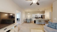Located at 2605 Sidbury Crossing Dr in Castle Hayne, NC, this well-appointed single-story home offers 3 bedrooms and 2 bathrooms across a thoughtfully designed floor plan. The open-concept living area seamlessly connects the living room, dining area, and kitchen, creating a welcoming and functional space. The living room features vaulted ceilings, a ceiling fan, and carpet flooring, while the dining area is illuminated by a stylish pendant chandelier and opens directly to the kitchen. The kitchen is a standout, boasting white cabinetry, granite countertops, stainless steel appliances including a refrigerator and dishwasher, a peninsula with bar seating, and pendant lighting above. Light wood-look flooring runs through the kitchen and dining area, adding a clean, modern feel. The spacious primary bedroom includes a ceiling fan, large windows with views of surrounding greenery, and a walk-in closet. Additional bedrooms are carpeted and filled with natural light. Both bathrooms are finished with tile flooring, neutral cabinetry, and brushed nickel fixtures. A dedicated laundry room with wire shelving and utility hookups adds everyday convenience. Throughout, neutral tones and consistent finishes create a cohesive and inviting atmosphere.