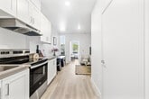 Located on W Martin Luther King Jr Blvd in the Baldwin Hills area of Los Angeles, this one-bedroom, one-bathroom unit offers a well-organized layout across a single floor. Light wood-style flooring flows consistently throughout, lending a clean, cohesive aesthetic to the space.

The living room features crisp white walls, a structural ceiling beam detail, and enough room for a comfortable seating arrangement. Natural light and a neutral palette create an inviting atmosphere suitable for both relaxing and entertaining.

The kitchen is efficiently designed with white shaker-style cabinetry, gray quartz countertops, and stainless steel appliances including a range and refrigerator. Under-cabinet range hood ventilation and ample upper and lower storage make the kitchen both practical and polished.

The bedroom is a cozy, private retreat with a sliding-door closet, a textured accent wall behind the bed, and a window with outdoor views, complemented by a wall-unit air conditioner for climate control.

The bathroom maintains the unit's clean, minimal aesthetic with light flooring, white walls, a bathtub with shower curtain, and simple, functional fixtures. The monochromatic accents add a subtle stylistic touch throughout.
