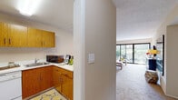This single-floor residence offers a thoughtfully designed layout that balances comfort and functionality throughout. The kitchen is equipped with warm wood-toned cabinetry, ample upper and lower storage, light countertops, a stainless steel sink, and a dishwasher — providing a practical and efficient workspace. It connects seamlessly to the living area, which features plush carpeting, neutral walls, and a wall of floor-to-ceiling sliding glass doors that bathe the space in natural light and open to a private patio with serene garden and tree views.

The primary bedroom is a standout, offering sliding glass door access to a private outdoor patio surrounded by lush greenery, mirrored closet doors, and soft carpeting underfoot. A second bedroom features its own window overlooking the exterior, a closet, and warm, neutral tones. Both rooms offer a calm and restful atmosphere.

The bathroom includes a marble-style countertop vanity with ample under-sink storage, a large wall mirror, and a separate enclosed shower-tub combination with frosted glass doors and tile flooring.

Throughout the residence, a consistent palette of warm beige and neutral tones creates a cohesive and inviting ambiance, complemented by abundant natural light and well-considered connections to the outdoors.