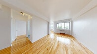 Located on the 5th floor at 6920 Avenue Fielding in the NDG neighbourhood of Montréal, this one-bedroom, one-bathroom unit offers a well-proportioned and functional layout. Gleaming hardwood floors flow throughout the living areas, reflecting natural light and lending a warm, inviting character to the space.

The living room is generously sized, featuring clean white walls, large windows that frame outdoor views of the surrounding greenery, and a classic radiator heating unit beneath the sill. The bright, airy atmosphere is further enhanced by the open sightlines connecting the living room to the entrance hallway.

The primary bedroom is a spacious retreat, easily accommodating large furniture, with the same polished hardwood flooring and ample wall space. A closet provides practical storage within the room.

The bathroom features classic pink wall tiling and mosaic floor tiles, with a combined tub and shower enclosed by sliding glass doors, a vanity with under-sink storage, and mirrored medicine cabinets above — a retro aesthetic that adds character to the space.

A welcoming entrance foyer with a solid wood door provides a natural transition into the unit, connecting to the hallway that links all rooms. The overall layout is efficient and cohesive, making excellent use of the available floor area throughout.