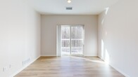 Located at 173 Monadnock Highway in Swanzey, New Hampshire, this well-appointed one-bedroom, one-bathroom unit offers a thoughtfully designed single-floor layout that makes excellent use of its compact footprint. Light-colored walls and a neutral palette create a clean, cohesive atmosphere throughout.

The kitchen stands out as a centerpiece of the space, featuring a two-tone cabinet design with crisp white upper cabinets and warm wood-toned lower cabinets, complemented by white quartz countertops and a light blue glass tile backsplash. Stainless steel appliances — including a refrigerator, range, microwave, and dishwasher — add a modern touch, while a central island with pendant lighting provides additional prep space and casual seating.

The living room is bright and welcoming, with light hardwood-style flooring and a sliding glass door that opens to a private balcony overlooking a wooded tree line, filling the room with natural light and peaceful outdoor views.

The bedroom is carpeted for comfort and features a window with scenic wooded views, along with access to a closet. The full bathroom is finished with tile flooring, warm wood cabinetry with ample storage, a combination tub and shower, and matte black hardware accents that tie the design together cohesively. Two hallways connect the spaces efficiently, completing this well-organized and functional home.