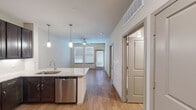 Located at 3640 Harmony Commons Drive in Spring, TX, this well-designed one-bedroom, one-bathroom unit offers a smart, functional layout across a single floor. The open-concept kitchen and living area serves as the heart of the home, anchored by a peninsula with granite countertops, a stainless steel undermount sink, and pendant lighting above. Dark espresso cabinetry lines the kitchen walls, complemented by a full suite of stainless steel appliances including a range, over-the-range microwave, dishwasher, and refrigerator, along with a classic white subway tile backsplash. Hardwood-style flooring flows throughout the main living area, which benefits from natural light streaming through multiple windows fitted with blinds, and a ceiling fan overhead. The bedroom is carpeted and comfortably sized, with a ceiling fan, a window for natural light, and direct access to a spacious walk-in closet outfitted with built-in shelving and multiple hanging rods. The bathroom echoes the kitchen's design language, featuring granite countertops, a dark wood vanity, an undermount sink, and a large framed mirror with overhead cabinetry for additional storage. This unit offers a cohesive, modern aesthetic throughout with practical, well-appointed finishes.