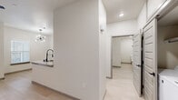Located at 13612 Hazlewood St in Horizon City, TX, this single-story home offers a thoughtfully designed layout with modern finishes throughout. The interior features light wood-tone flooring that runs continuously across all rooms, contributing to a bright, cohesive aesthetic paired with crisp white walls and recessed lighting.

The kitchen is a standout feature, boasting a galley-style configuration with white shaker upper cabinets and contrasting gray lower cabinets, all topped with granite countertops. A stainless steel sink with a sleek black spring-neck faucet anchors the prep area, while stainless steel appliances — including a refrigerator, range, and over-the-range microwave — complete the space. A pass-through window connects the kitchen to the adjacent living area, enhancing the open feel.

The bedroom is a comfortable and well-lit retreat, featuring two windows with blinds that allow natural light to fill the room, along with a ceiling fan overhead. A generously sized closet with double panel doors and built-in shelving and hanging rods provides ample storage.

The bathroom features a dark-toned vanity with granite countertops and black hardware accents, complemented by marble-look tile wall detailing. The clean, modern design extends throughout with consistent use of neutral tones and quality materials, creating a polished and functional living environment.