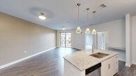 Located at 5100 Forest Ave in Downers Grove, IL, this well-appointed one-bedroom, one-bathroom residence offers a thoughtfully designed open-concept layout with modern finishes throughout. The combined kitchen and living area serves as the heart of the home, anchored by a curved granite-topped island with an undermount sink and elegant pendant lighting. The kitchen is equipped with stainless steel appliances, including a French door refrigerator, gas range, and built-in microwave, all complemented by crisp white cabinetry and a classic tile backsplash. Wood-style plank flooring extends throughout the main living areas, adding warmth and continuity. The living room features a sliding glass door that opens to a private balcony, offering outdoor views of the surrounding neighborhood. The bedroom is carpeted for comfort, features a large window that brings in natural light, and provides direct access to a walk-in closet with wire shelving. The full bathroom is finished with large-format tile flooring, a granite vanity, and sleek modern cabinetry. A dedicated in-unit laundry room accommodates a full-size side-by-side washer and dryer, adding everyday convenience to this polished and functional Downers Grove residence.