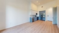 Located at 501 NW Seventh Terrace in Fort Lauderdale, FL, this modern one-bedroom, one-bathroom unit offers a thoughtfully designed open-concept layout with clean contemporary finishes throughout. The combined living, dining, and kitchen area is the heart of the unit, distinguished by soaring ceilings that amplify the sense of space. Light-toned hardwood-style flooring runs throughout, complementing the bright white walls and lending a cohesive, airy feel. Floor-to-ceiling black-framed glass doors open onto a private balcony, flooding the living area with abundant natural light and offering pleasant tree-lined outdoor views. The kitchen features sleek two-tone cabinetry — crisp white upper cabinets paired with matte blue-gray lower cabinets — a white tile backsplash, a matte black faucet, and stainless steel appliances including a dishwasher, range, microwave, and a paneled refrigerator. The bedroom is a well-proportioned retreat accessed through a stylish sliding barn door with matte black hardware, continuing the modern aesthetic. The bathroom is finished with large-format tile flooring, a navy blue vanity with a white countertop, and a full tub and shower. Three closets and an in-unit laundry area provide excellent storage and convenience throughout this efficiently designed Fort Lauderdale residence.