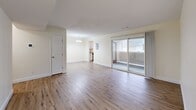 Located at 26 Beacon St in Burlington, MA, this 2-bedroom, 1-bathroom residence offers a well-organized single-floor layout with a clean, neutral aesthetic throughout. The expansive main living area is anchored by light-toned hardwood-style flooring and cream-colored walls, creating a bright and welcoming atmosphere. Large sliding glass doors flood the space with natural light and provide direct access to a private outdoor balcony. A pendant light fixture marks the transition into a secondary living or dining area, which connects seamlessly to the kitchen. The kitchen is well-appointed with white shaker-style cabinetry, granite countertops, a stainless steel sink, dishwasher, range, and microwave, all set atop matching hardwood-style flooring. Both bedrooms feature plush carpeting and soft neutral tones. The generously sized primary bedroom includes a double-door closet, while the second bedroom offers comfortable proportions with easy hallway access. A dedicated closet provides additional storage. The full bathroom is finished with tile flooring and includes a tub-shower combination. A hallway connects all rooms efficiently, completing this thoughtfully laid-out and move-in-ready residence.